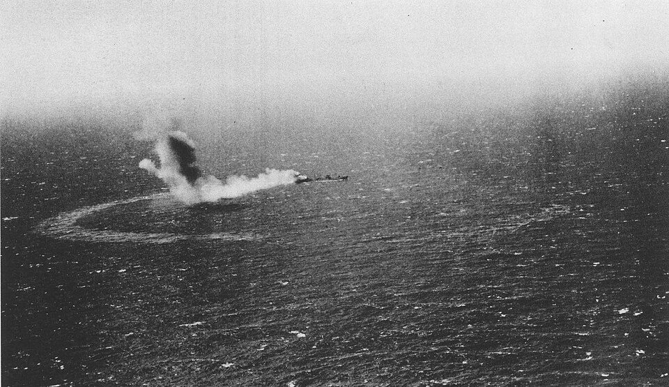 Neosho burning on 7 May 1942, a small ship in the smoke